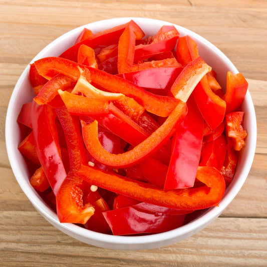 SLiced Red Capsicum in a white bowl on a wooden table