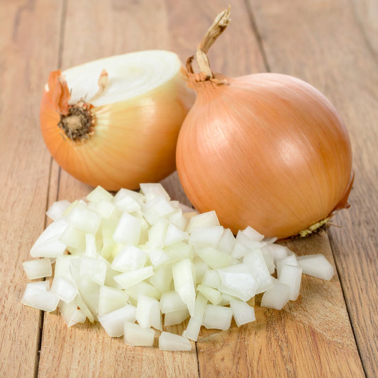Whole onions and chopped onions on a wooden surface