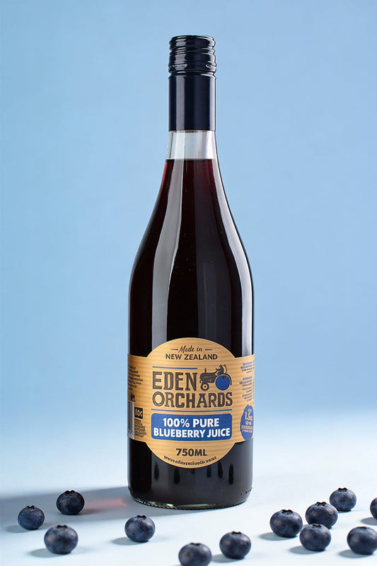 Bottle of Eden Orchards 100% Pure Blueberry Juice with blueberries on a light blue background