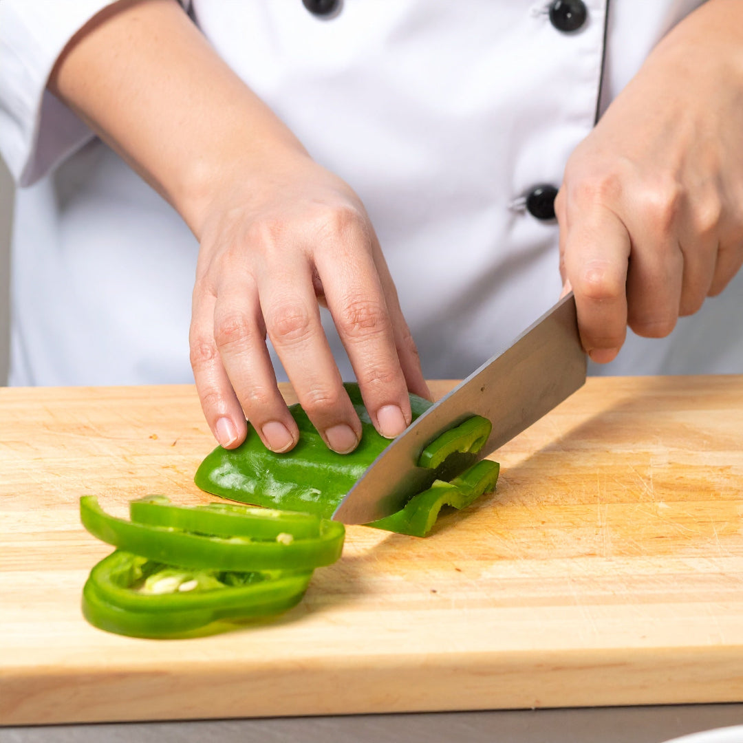 A chef slicing a capsicum into strips