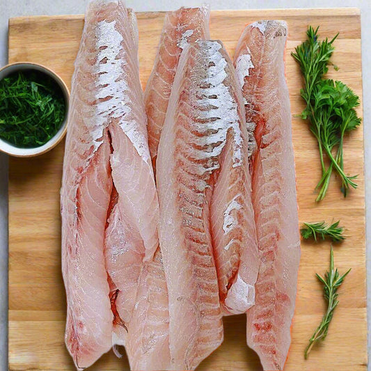 Gurnard fillets on a chopping board surrounded by herbs