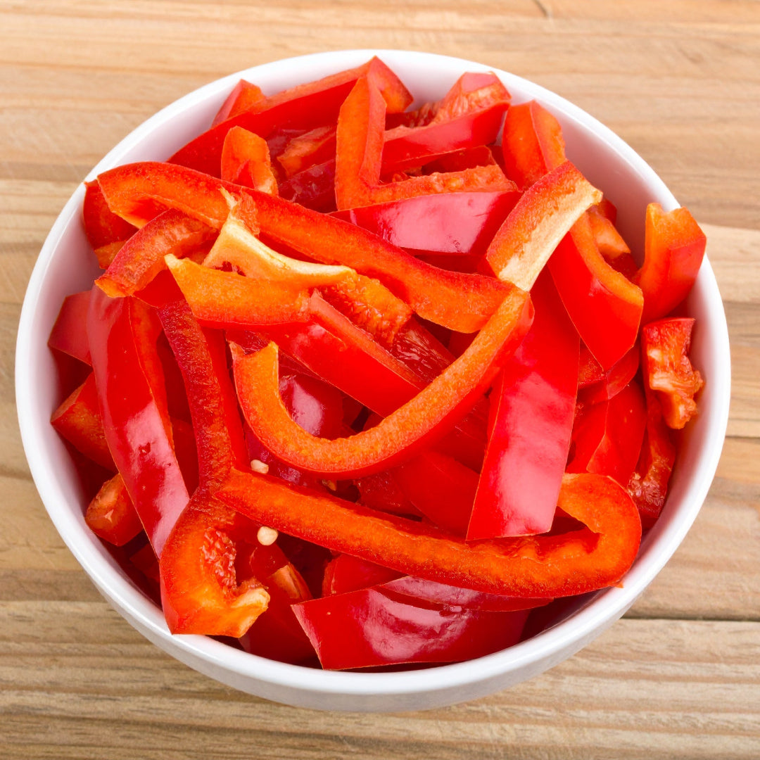 SLiced Red Capsicum in a white bowl on a wooden table