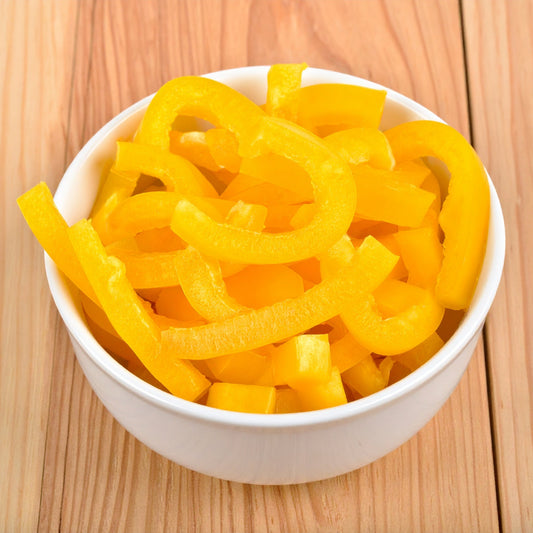 Sliced Yellow Capsicum in a white bowl on a wooden table